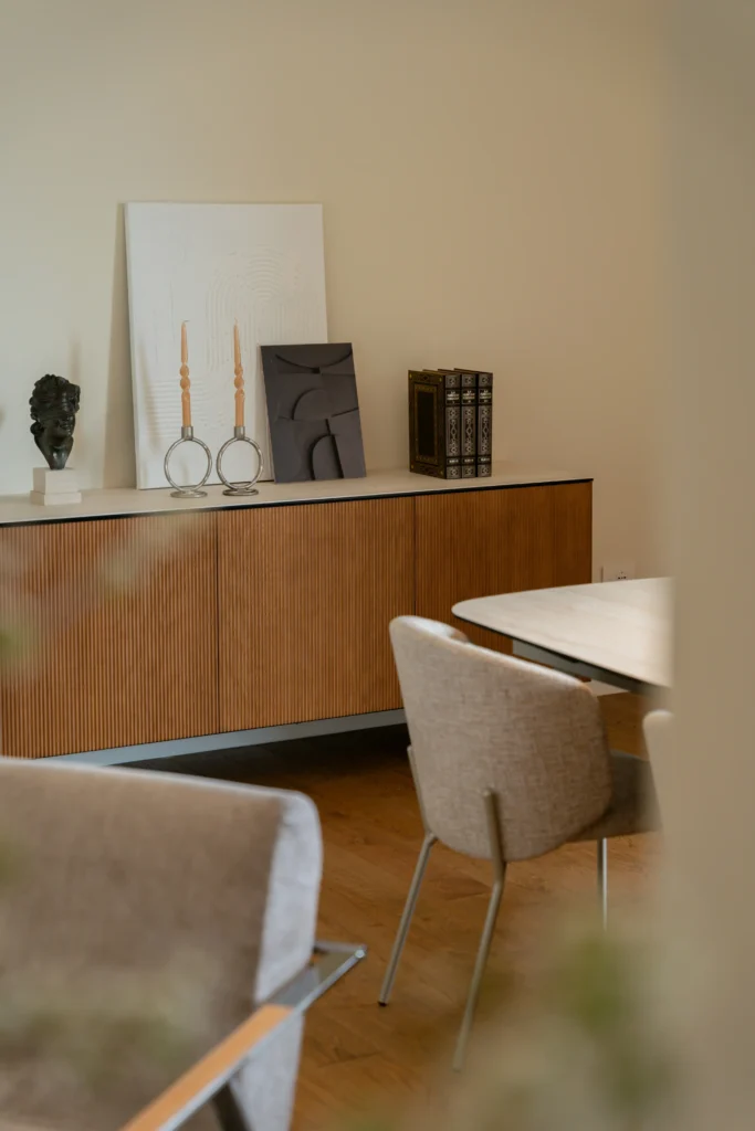 Elegancki kącik jadalniany z komodą w drewnianym wykończeniu, designerskimi świecznikami i nowoczesnymi dekoracjami.