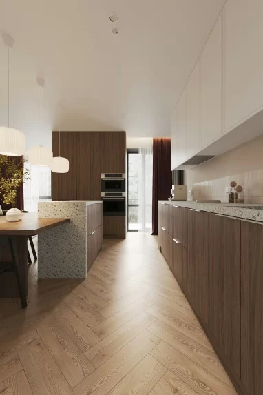 Drewniana kuchnia w układzie galley z wyspą z terrazzo, długim blatem i herringbone parkietem; na lewo stół jadalniany z białymi lampami.